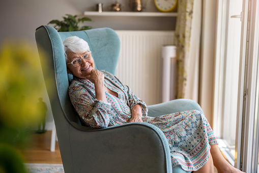Elderly woman sitting in an armchair in her home