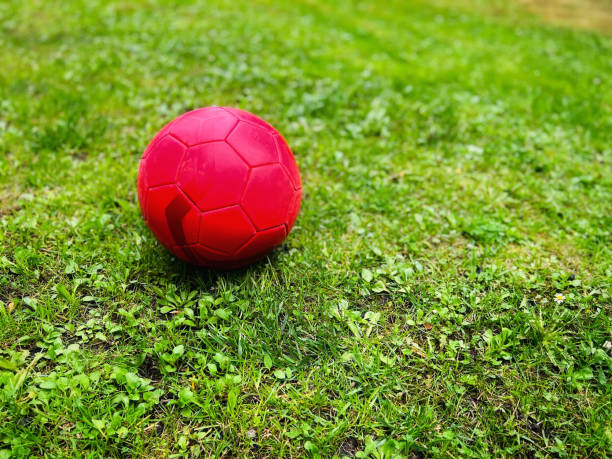 Red soccer ball on green grass. Selective focus