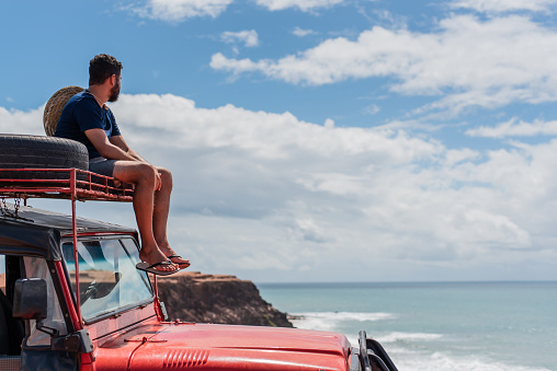 Tourist contemplating the beach in off road car, Rio Grande do Norte, Brazil