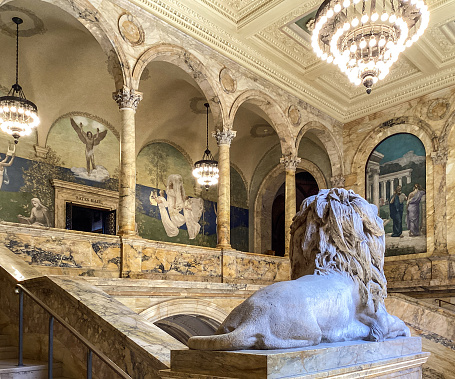 Boston, Massachusetts, USA - May 18, 2022: Interior view of the Grand Staircase and the Puvis de Chavannes Gallery at The Boston Public Library. Encircling the main staircase are eight panels representing disciplines that one could pursue in the library. The Boston Public Library contains approximately 24 million items, making it the third-largest public library in the United States behind the federal Library of Congress and the New York Public Library.