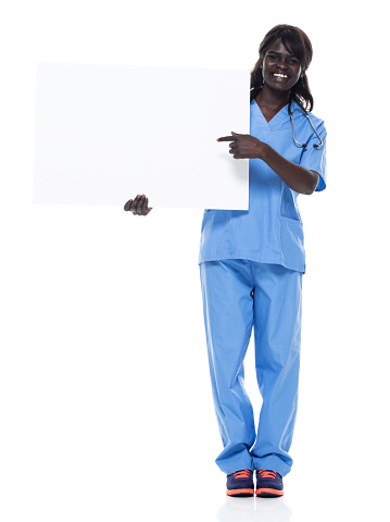 One person of aged 20-29 years old who is beautiful with long hair african-american ethnicity female standing in front of white background wearing sports shoe who is cheerful who is showing with hand and holding placard with copy space