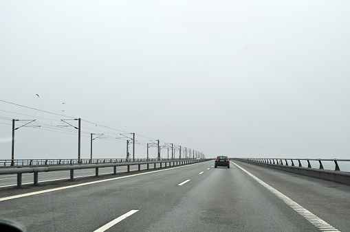 A road leading to a bridge that connects Sweden and Denmark in northern Europe. Traveling in ugly rainy weather.