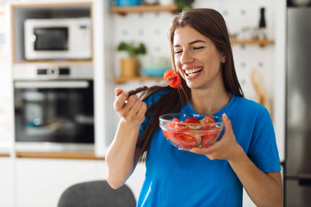 Smiling  woman eating salad in the kitchen