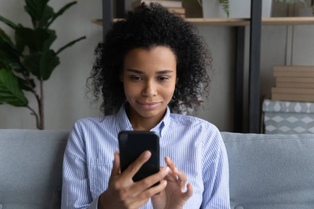 istock Smiling young African woman using telephone at home. 1402192419