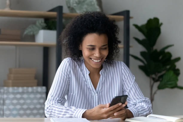 istock Smiling young African woman using cellphone in office. 1402192482