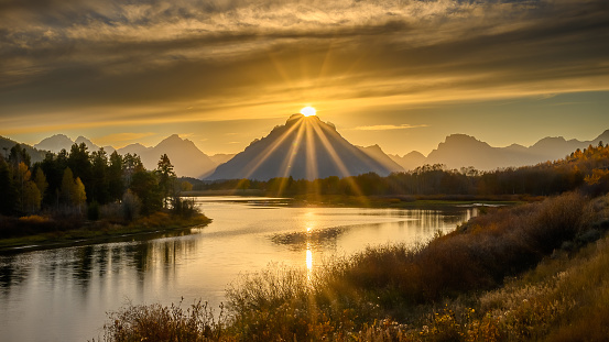 Sun setting behind the mountains at Oxbow Bend Overlook in Grand Teton National Park in Wyoming