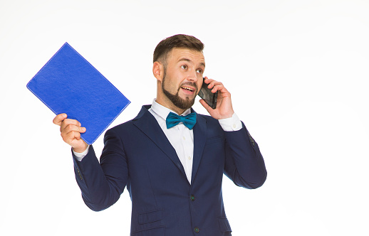 cheerful guy with a phone and a blue folder posing in a blue jacket on a white background isolated in the studio