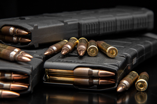 Hand gun with ammunition on dark background. 9 mm pistol military weapon and pile of bullets ammo at the metal table.