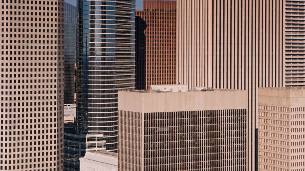 Aerial shot of the midsections of office towers in Houston, Texas on a late sunny afternoon.\n\nAuthorization was obtained from the FAA for this operation in restricted airspace
