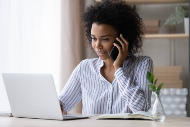istock Focused beautiful millennial African ethnicity woman multitasking in office. 1402198813