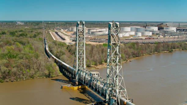 Aerial View of Train and Industrial Facilities in Beaumont, Texas Aerial establishing shot of a freight train crossing the Neches River in Beaumont, Texas on a clear sunny afternoon. beaumont tx stock pictures, royalty-free photos & images