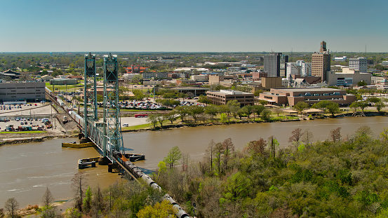 Aerial establishing shot of a freight train crossing the Neches River in Beaumont, Texas on a clear sunny afternoon.