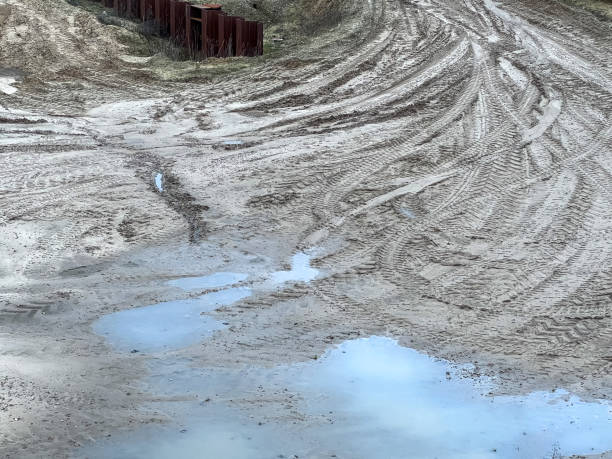 Sandy soil with tracks and puddles of water on a construction site.