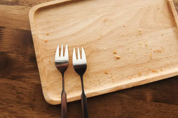 Two fork on tray wood texture with crumb on the table