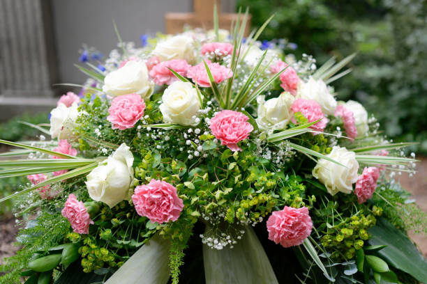 pastel funeral flowers on a grave pastel funeral flowers on a grave in front of a wooden cross in blurred background flower arrangement stock pictures, royalty-free photos & images