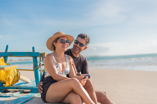 Tourist couple using smartphone on the beach