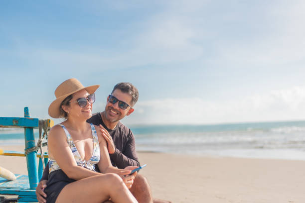 istock Tourist couple using smartphone on the beach 1402204552