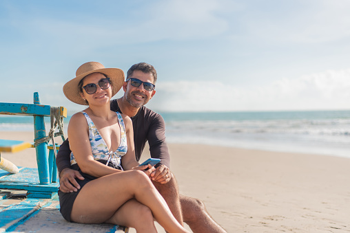 Portrait of smiling tourist couple sitting on the beach