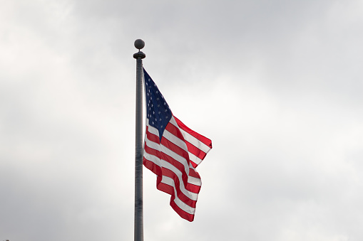 Beautiful American flag waving in the wind, with vibrant red white and blue colors against blue sky