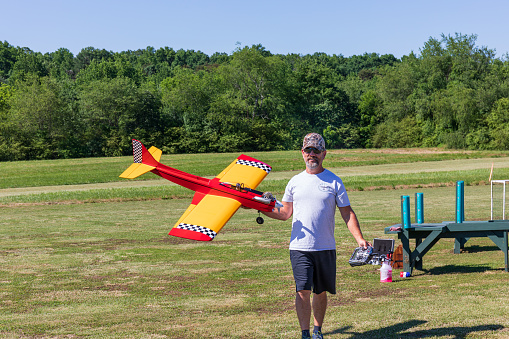Bethlehem, NC, USA-28 May 2022: Proud owner holds gas powered radio-controlled model plane on an exhibition day.