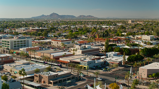 Aerial shot of Mesa, a city within the Phoenix metropolitan area, on a sunny day in spring, including a train on Valley Metro light rail system tracks along Main Street.