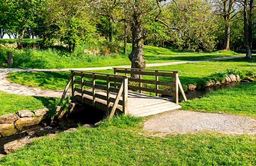 A small wooden bridge across the stream in a small public park near \