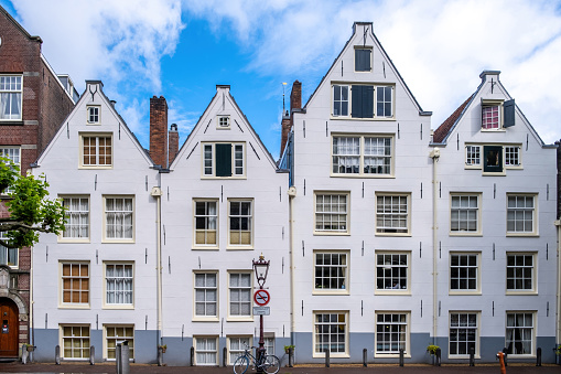 Amsterdam houses, white color facade and windows, bicycle parked outside. Building in residential neighborhood, Holland Netherlands