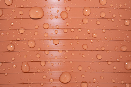 Close up of an orange plastic flower pot witha lot raindrops