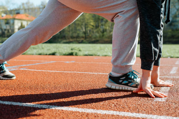 istock Outdoor training, caucasian woman practicing jogging on stadium, standing at start on sunny day. Sports, active lifestyle, weight loss. Close-up, side view 1402246731