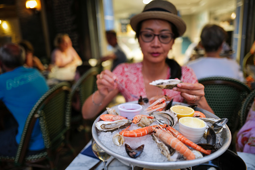 Woman eating a seafood and oyster, close-up at a restaurant