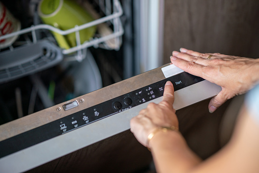 Close-up of female hand setting cycle on dishwasher