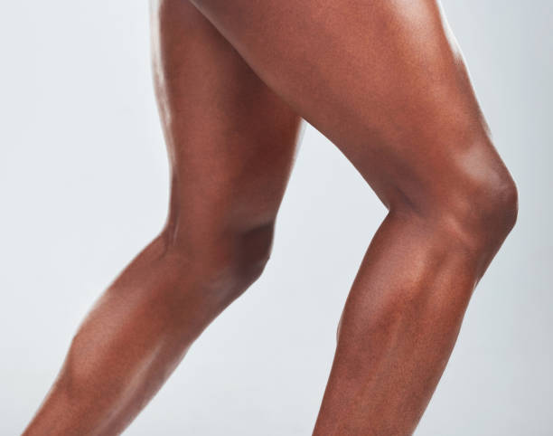 closeup of one  african american fitness model posing and looking muscular. confident black male athlete isolated on grey copyspace in a studio showing his strong, toned legs - bending knees imagens e fotografias de stock