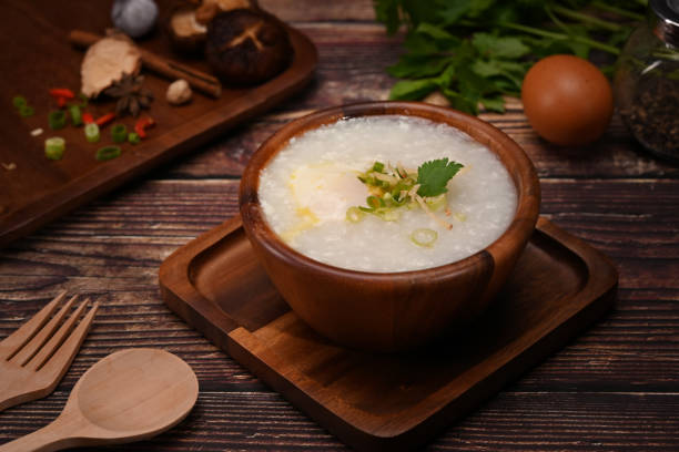 istock Rice porridge or congee with soft boiled egg, slice ginger and slice scallion topping on wooden table. 1402256785