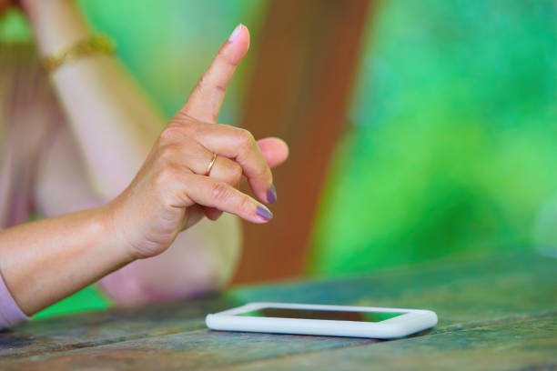 istock Raised index finger in front of the phone lying on the table. 1402256866