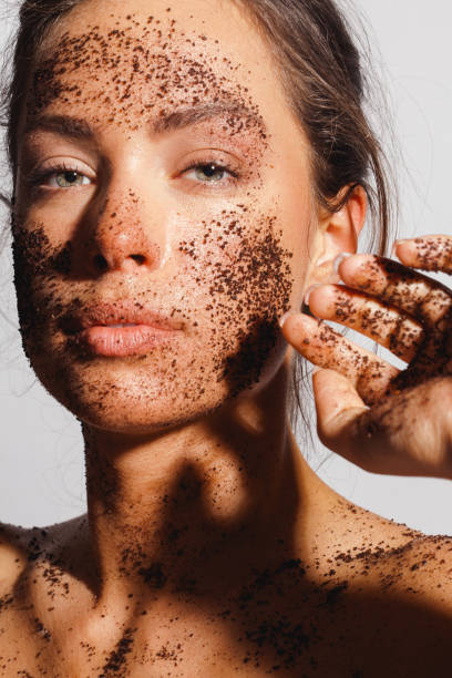 Beauty portrait of a young woman with ground coffee over her clean healthy skin stock photo