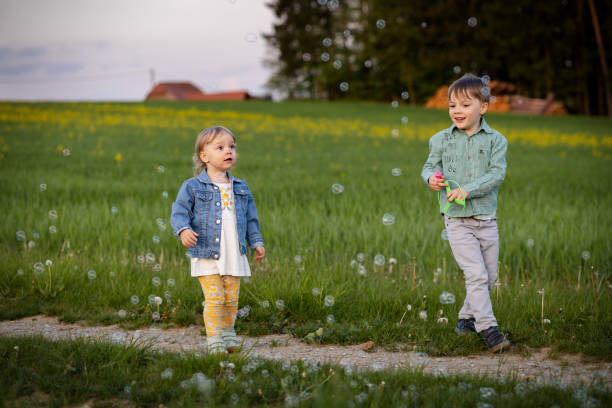 due bambini che corrono su un campo verde tra i fiori - huckleberry finn foto e immagini stock