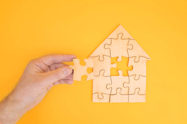 istock Puzzle house with a missing piece in mans hand. The acquisition or construction comfortable dream home. Mortgage loan purchase real estate. Arrangement premises repair. Availability and cheapness. Finish building 1402266653