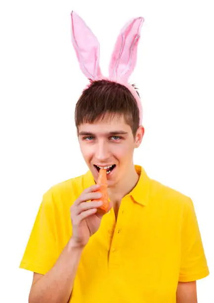Young Man in Bunny Ears and with a Carrot Isolated on the White Background