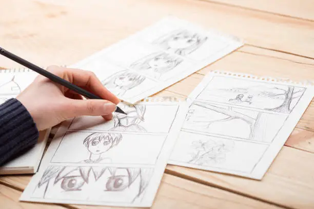 Photo of Artist drawing an anime comic book in a studio.