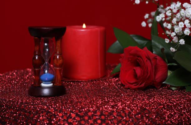 A table set with a red tablecloth, adorned with roses, and a gift, ready for a Valentine's Day celebration