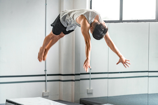 Asian Man Acrobatic Dive in Gym Studio