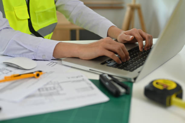 istock Cropped view foreman engineer or architecture's hand working on a laptop with tools and machine on the table in the office, for engineering, architect, business, safety and technology concept. 1402272824
