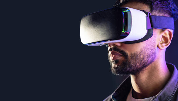 istock Young man experiencing virtual reality eyeglasses headset, isolated on black background 1402276190