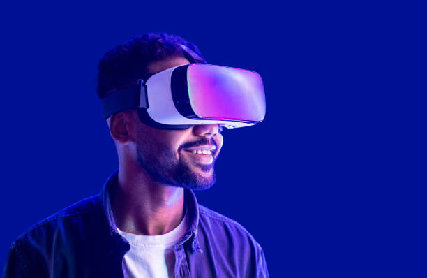 istock Young man experiencing virtual reality eyeglasses headset, isolated on blue background 1402276191