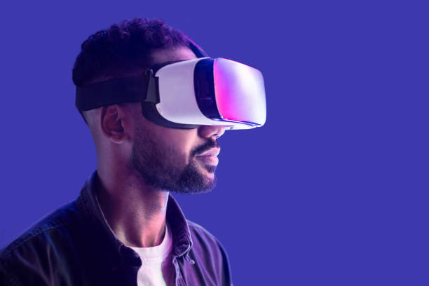 istock Young man experiencing virtual reality eyeglasses headset, isolated on blue background 1402276195