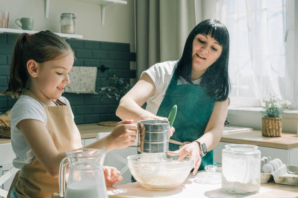 istock Mother and daughter making dough on kitchen. 1402276944