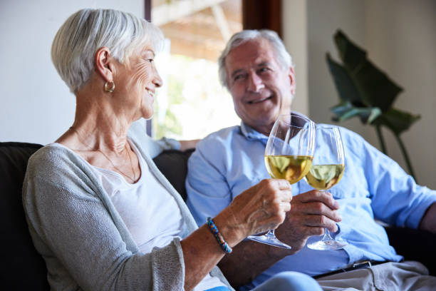 istock Smiling senior couple toasting together with wine on their sofa 1402277161