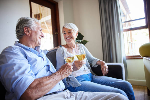 istock Laughing senior couple sitting on their sofa and toasting each other with wine 1402277218