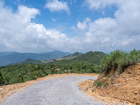 An empty unfinished road leading to the distance under the blue sky and white clouds