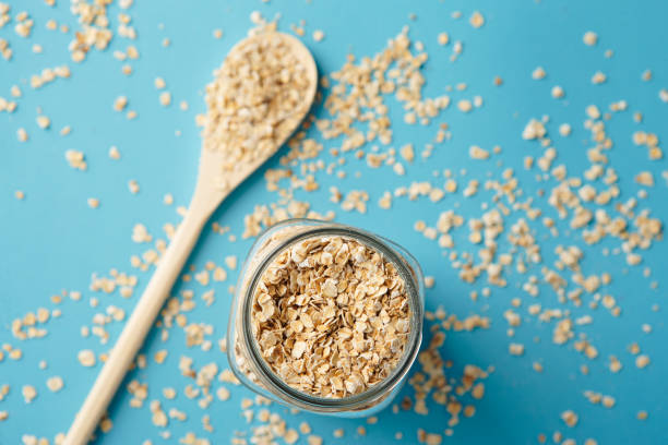 Above view of Mason jar over flowing with oatmeal flakes on blue background.